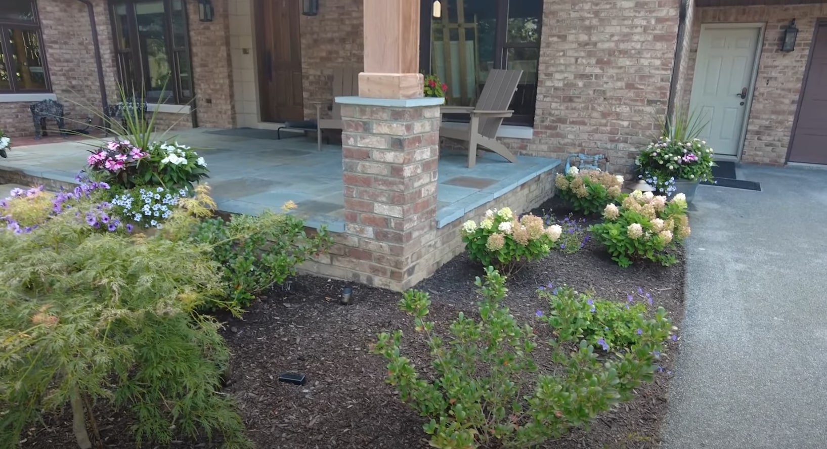 Elegant outdoor patio with stone columns, professional landscaping, and well-designed outdoor living space