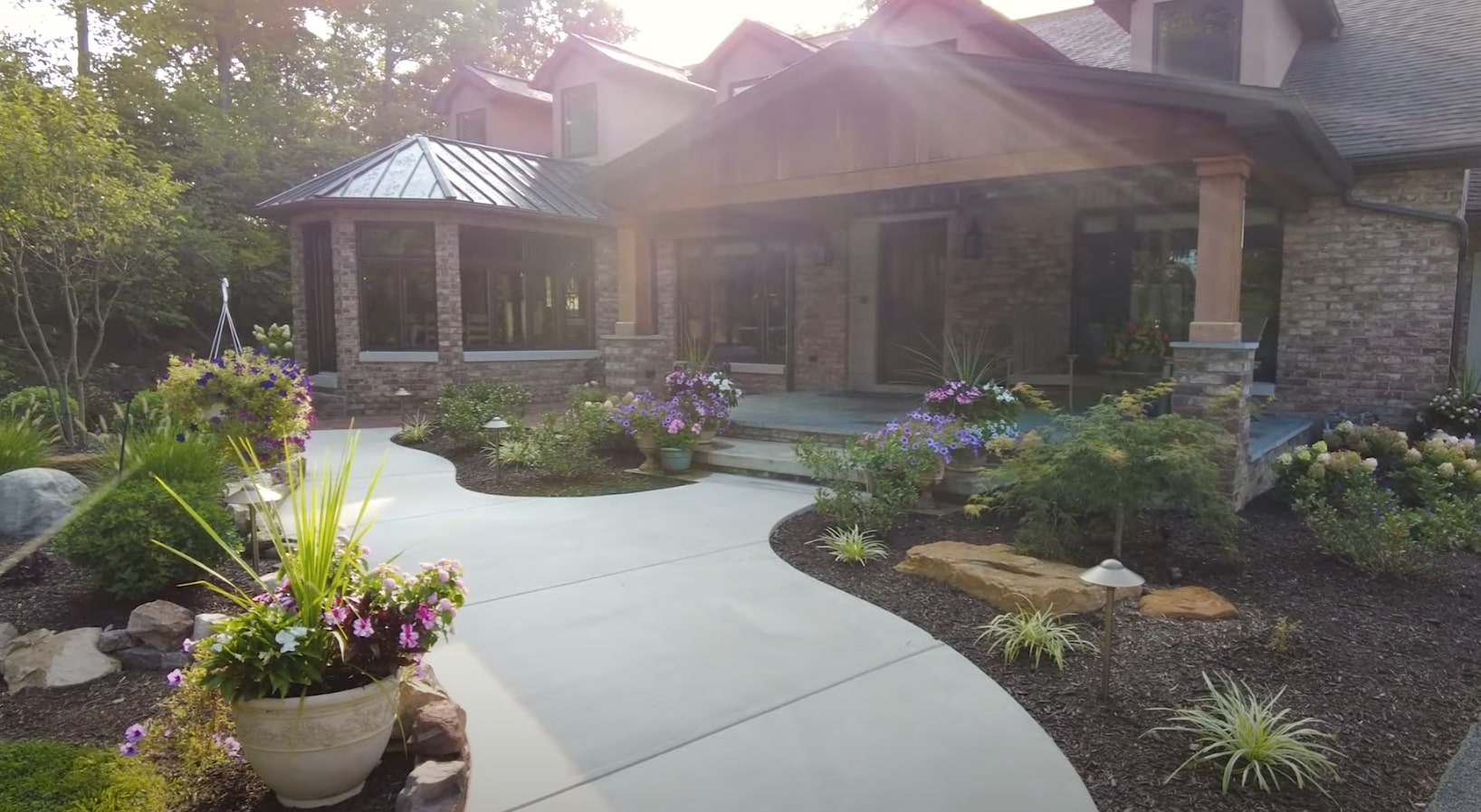 Beautiful landscaped home entrance with stone pathways, colorful flower beds, and professional hardscaping in Goodyear, Arizona