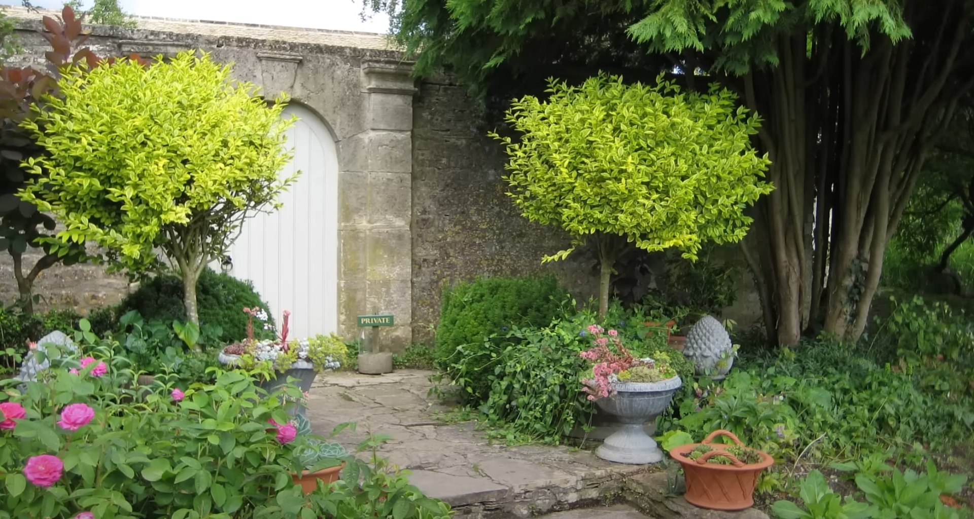 Elegant garden entrance with stone archway, decorative planters, and perfectly manicured landscaping