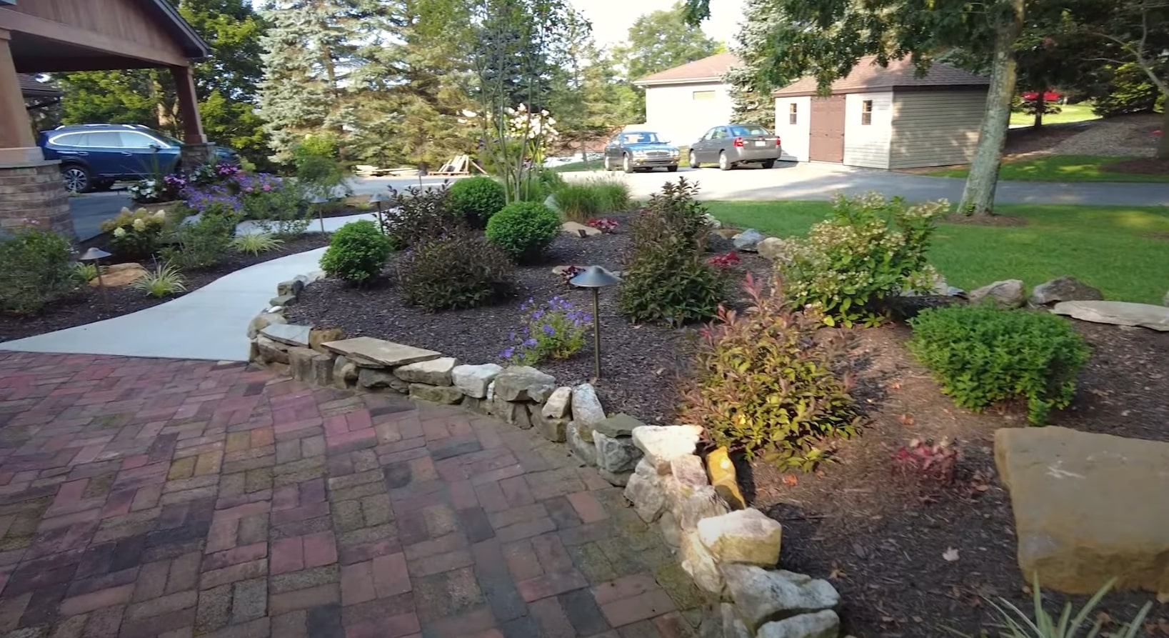 Beautiful residential landscape design with stone pathways, colorful flower beds, and professional hardscaping